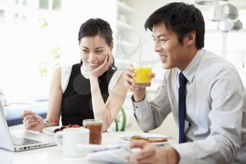 Asian Couple Looking at Laptop Over Breakfast