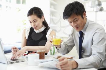 Asian Couple With Laptop And Newspaper At Breakfast