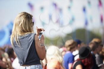Young Woman At Outdoor Music Festival Using Mobile Phone