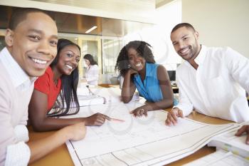 Group Of Architects Discussing Plans In Modern Office