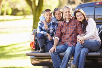 Family Sitting In Pick Up Truck On Camping Holiday