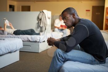 Men Sitting On Beds In Homeless Shelter