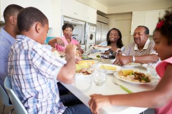 Multi-Generation Family Sitting Around Table Eating Meal