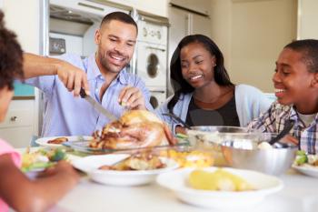 Family Sitting Around Table At Home Eating Meal