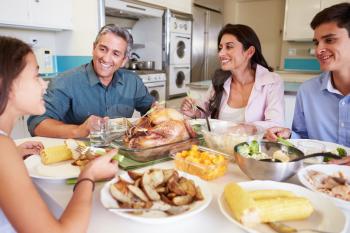 Family Sitting Around Table At Home Eating Meal