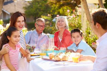 Multi-Generation Family Enjoying Outdoor Meal In Garden