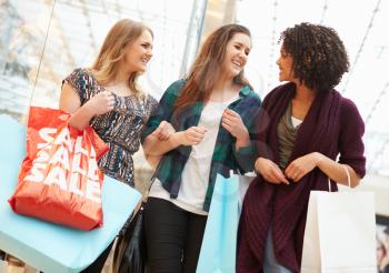 Excited Female Shoppers With Sale Bags In Mall