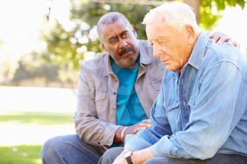 Man Comforting Unhappy Senior Friend Outdoors