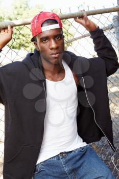 Portrait Of Young Man In Urban Setting Standing By Fence