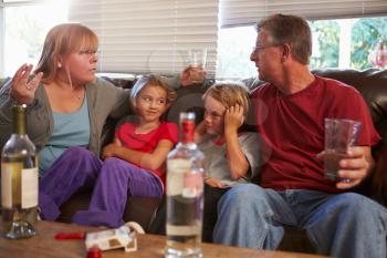 Parents Arguing On Sofa With Children Smoking And Drinking