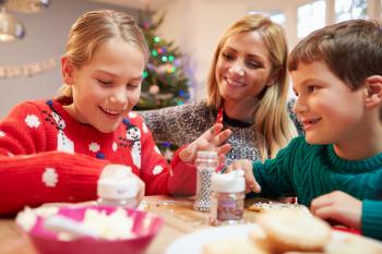 Mother And Children Decorating Christmas Cookies Together