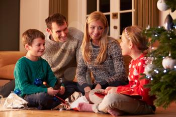 Family Unwrapping Gifts By Christmas Tree