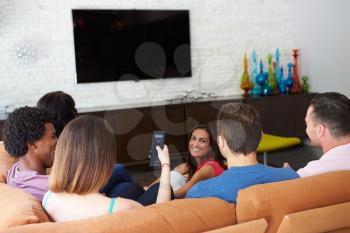 Group Of Friends Sitting On Sofa Watching TV Together