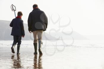 Father And Son Walking On Winter Beach With Fishing Net