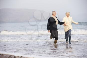 Senior Couple Running Along Winter Beach