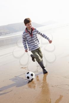 Boy Playing Football On Winter Beach