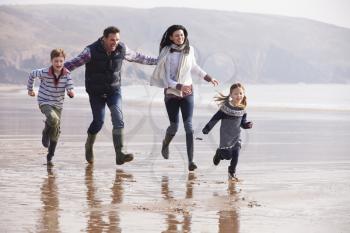 Family Running Along Winter Beach