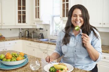 Overweight Woman Eating Healthy Meal In Kitchen