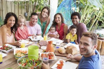 Group Of Families Enjoying Outdoor Meal At Home