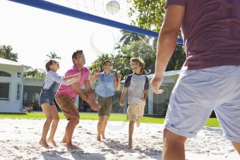 Family Playing Volleyball In Garden At Home