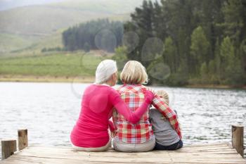 Mother, daughter and grandmother sitting on a jetty