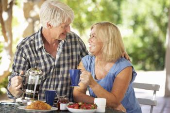 Senior couple eating breakfast outdoors