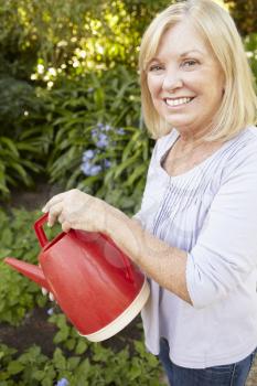 Senior woman watering garden