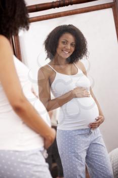 Pregnant woman looking in mirror