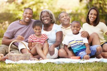 Multi Generation Family Enjoying Picnic In Garden Together