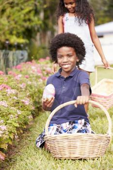 Two Children On Easter Egg Hunt In Garden