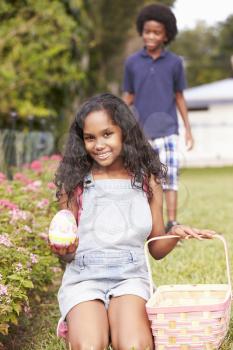 Two Children On Easter Egg Hunt In Garden