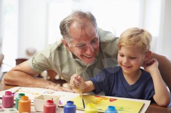 Grandfather Painting Picture With Grandson At Home