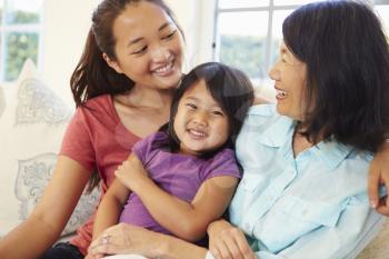 Grandmother Playing On Sofa With Granddaughter And Daughter