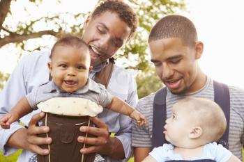 Two Fathers With Baby Carriers Walking In Park