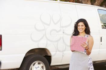Woman Wearing Apron With Clipboard In Front Of Van