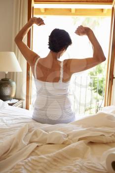 Rear View Of Woman Waking Up In Bed In Morning