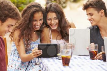 Teenage Friends Sitting At Caf Using Digital Tablets
