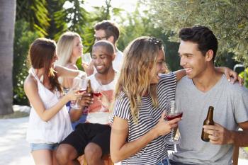 Couple With Friends Drinking Wine And Relaxing Outdoors