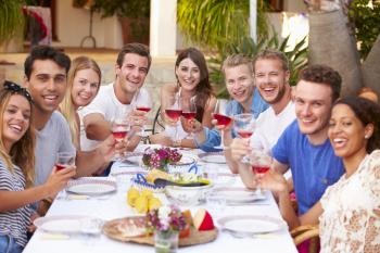 Large Group Of Young Friends Enjoying Outdoor Meal Together