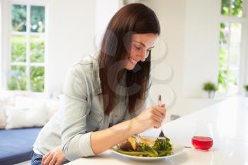 Woman Eating Healthy Meal In Kitchen