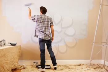 Man Decorating Room Using Paint Roller On Wall