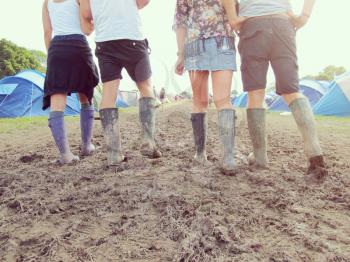 Close Up Of Friends In Wellington Boots Walking To Festival