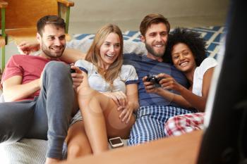 Group Of Friends Wearing Pajamas Playing Video Game Together