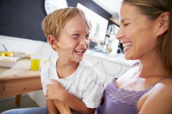 Mother Sitting With Laughing Son At Breakfast Table