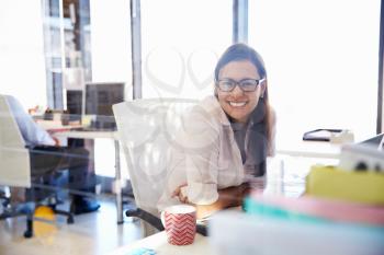 Woman at her desk in an office smiling to camera