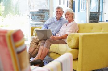 Senior Couple At Home In Lounge Using Laptop Computer