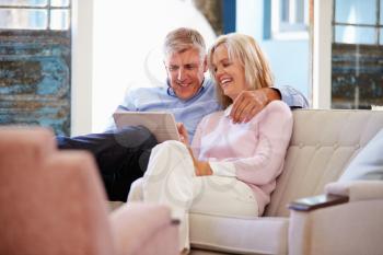 Mature Couple At Home In Lounge Using Digital Tablet