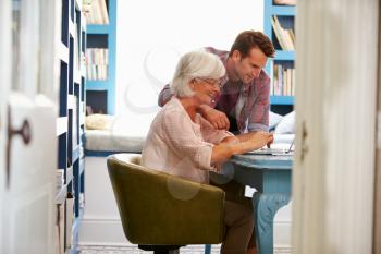 Son Giving Senior Parent Financial Advice In Home Office