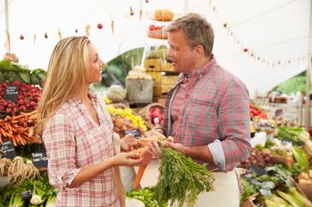 Woman Buying Fresh Vegetables At Farmers Market Stall