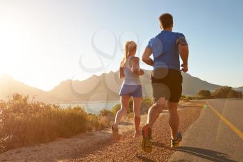Man and woman running together on an empty road